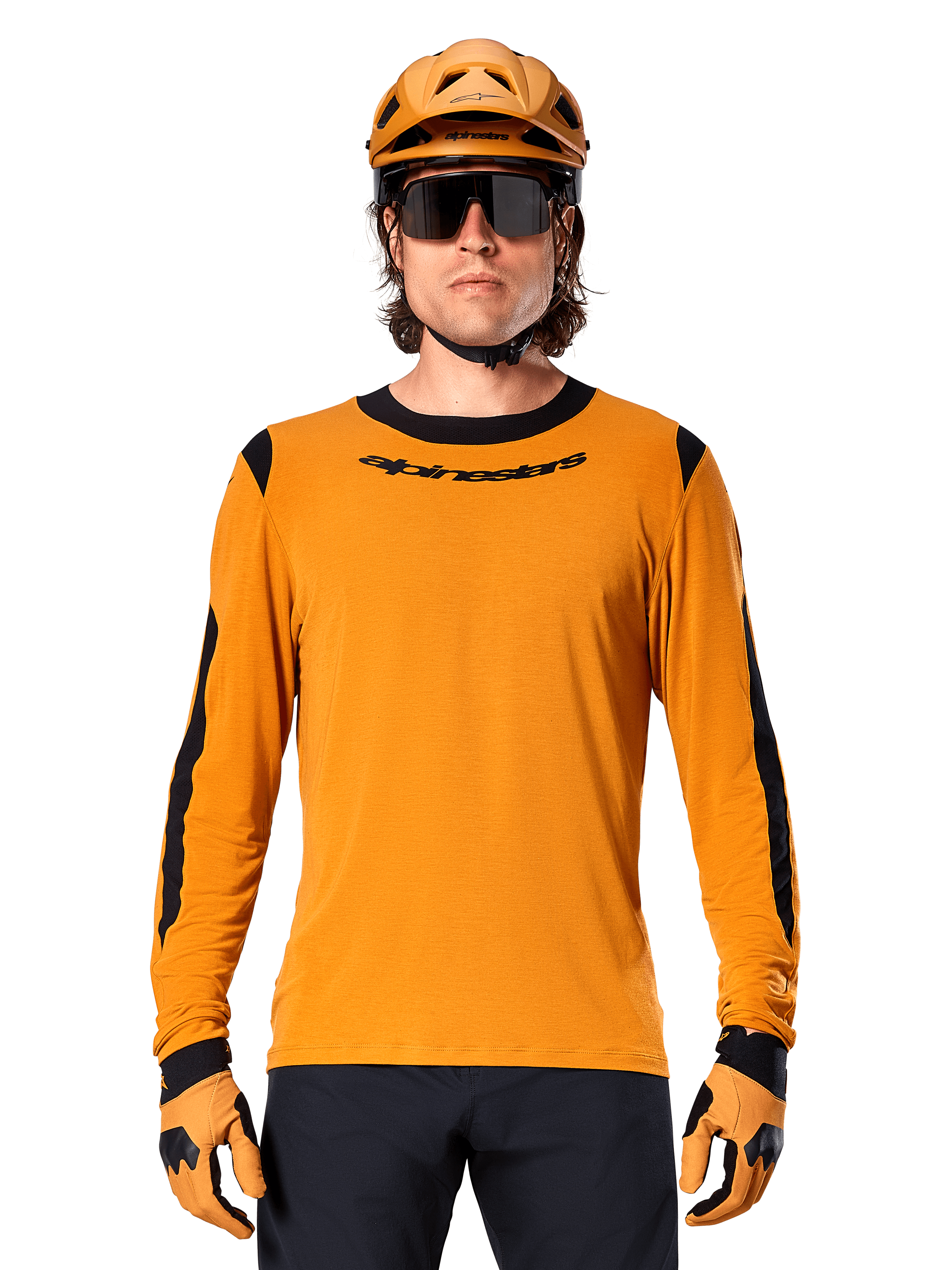 Modello che indossa la maglia a maniche lunghe Alpinestars A-Dura Dri Wool in Dark Gold, coordinata con casco da MTB e guanti oro abbinati, pannelli in rete nera su spalle e maniche, marchio Alpinestars nero sul petto, occhiali da sole e pantaloni scuri, abbigliamento tecnico da mountain bike