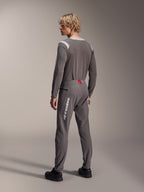 Modello visto da dietro con abbigliamento Alpinestars MTB, maglia a maniche lunghe A-Dura Dri Wool grigia, pantaloni A-Dura Elite grigio scuro con logo verticale bianco e dettaglio rosso in vita, completo coordinato da mountain bike