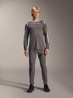 Maglia a maniche lunghe Alpinestars A-Dura Dri Wool, grigio scuro, indossata da un modello con pantaloni grigi coordinati e scarpe nere, logo Alpinestars bianco sul petto, pannelli in rete grigio chiaro su spalle e maniche, abbigliamento tecnico per mountain bike