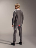 Modello che indossa la maglia a maniche lunghe Alpinestars A-Dura Dri Wool, grigio scuro con pannelli in rete grigio chiaro sulle spalle, abbinata a pantaloni da ciclismo coordinati, vista posteriore con orlo allungato, abbigliamento mountain bike