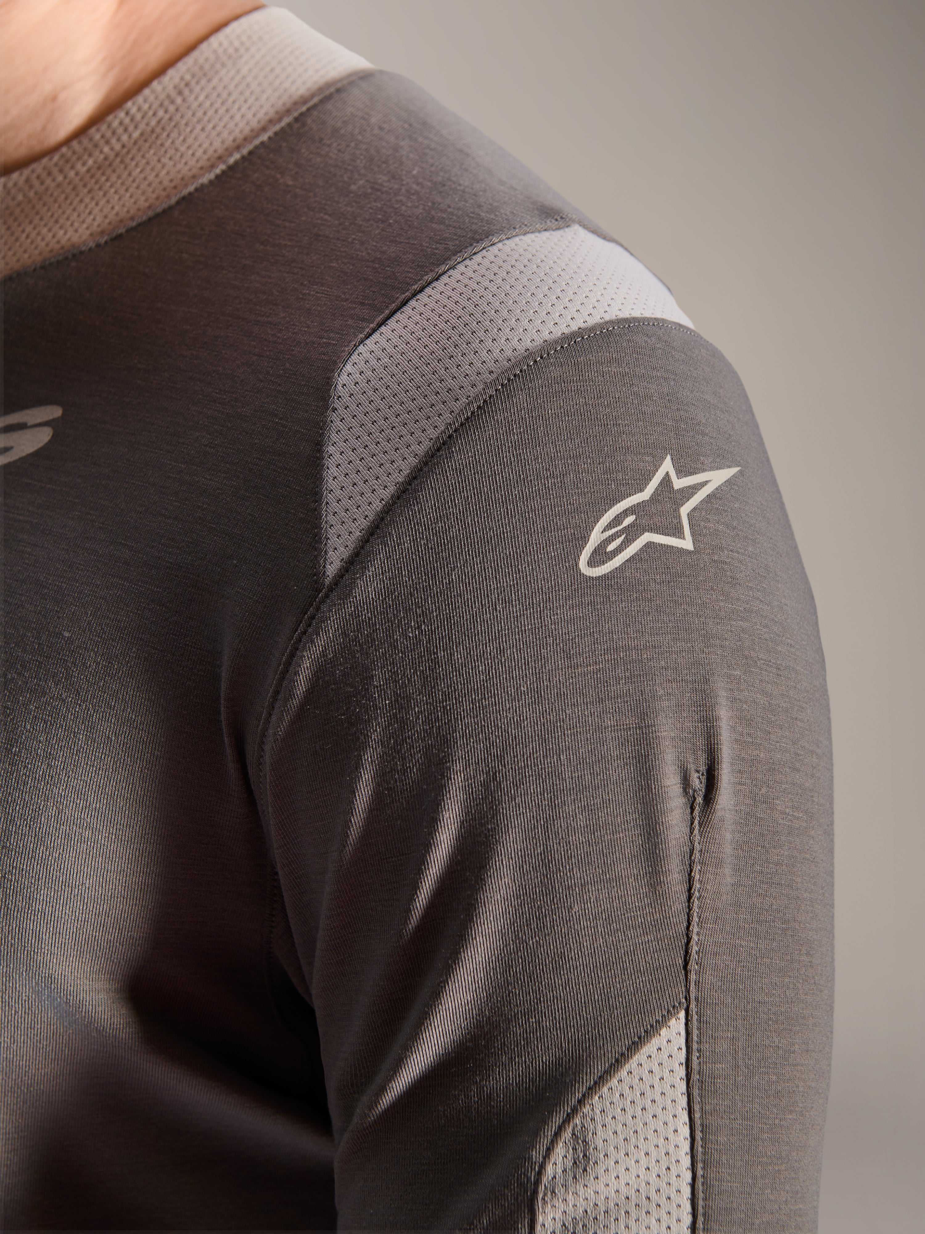 Alpinestars Maglia A-Dura Dri Wool - Manica Lunga, grigio scuro, vista dettagliata della spalla e della manica che mostra i pannelli di ventilazione in rete grigio chiaro e il logo Astars bianco sul tessuto tecnico drirelease.