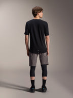 Alpinestars A-Dura Elite Shorts, pantaloncini da mountain bike grigio scuro, vista posteriore, indossati con maglia nera a maniche corte, ginocchiere e calze nere, abbigliamento tecnico da ciclismo per il fuoristrada