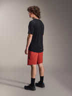 Alpinestars A-Dura Elite Shorts, pantaloncini da mountain bike, Dark Orange, indossati con una maglia nera a maniche corte e scarpe da mountain bike nere, vista laterale posteriore del modello che mette in risalto la vestibilità performante e il marchio