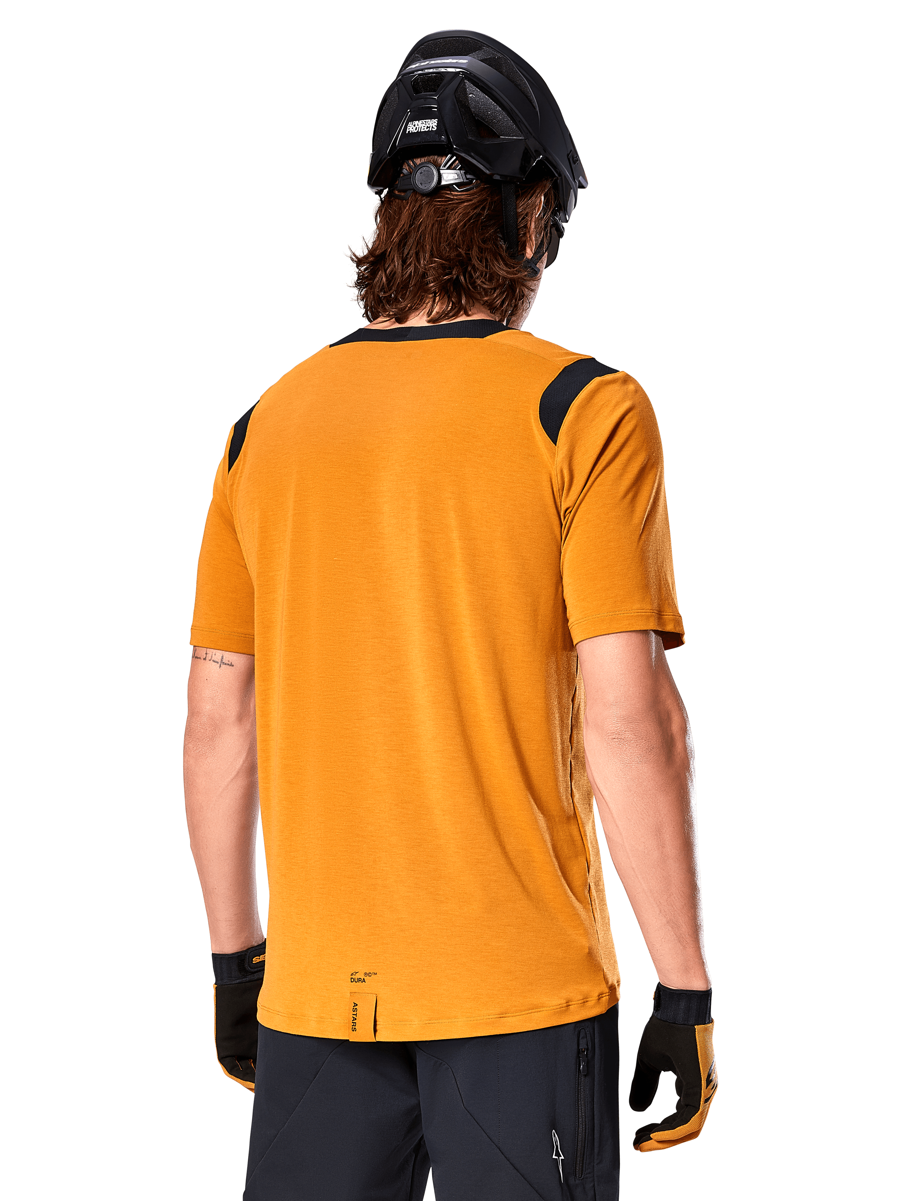 Alpinestars Maglia A-Dura Dri Wool a maniche corte, Dark Gold, vista posteriore di un uomo che indossa la maglia con pannelli in rete neri sulle spalle, abbinata a casco e guanti da MTB neri, abbigliamento da mountain bike con vestibilità regolare