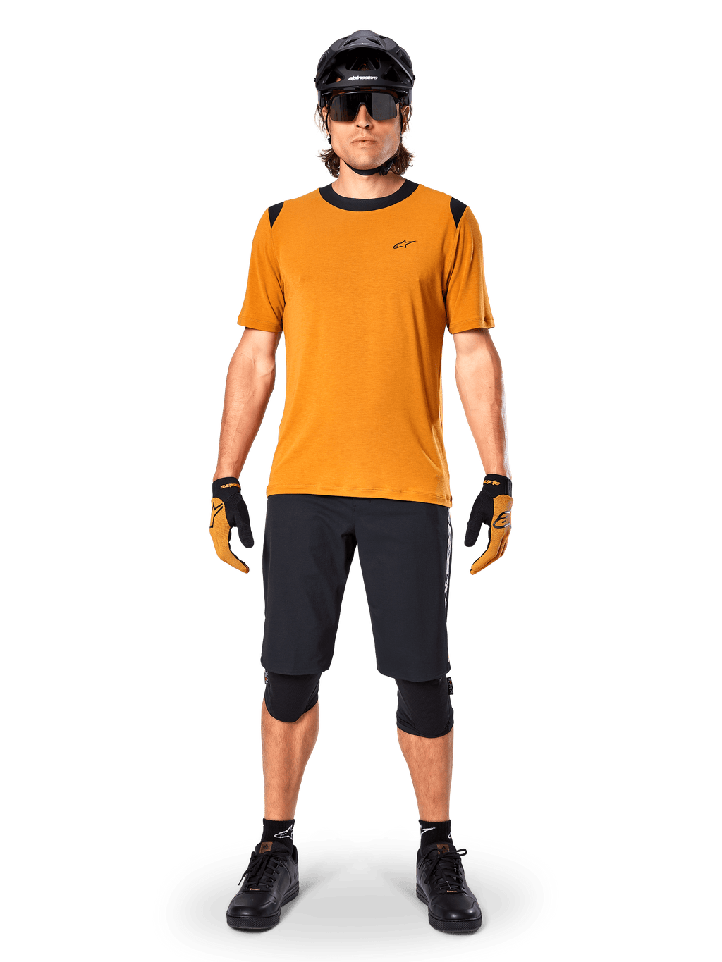 Alpinestars A-Dura Dri Wool Short Sleeve Jersey in Dark Gold, maglia da mountain bike a maniche corte, tessuto giallo senape con colletto e dettagli sulle spalle neri, indossata con pantaloncini neri e protezioni, abbigliamento tecnico da ciclismo per trail
