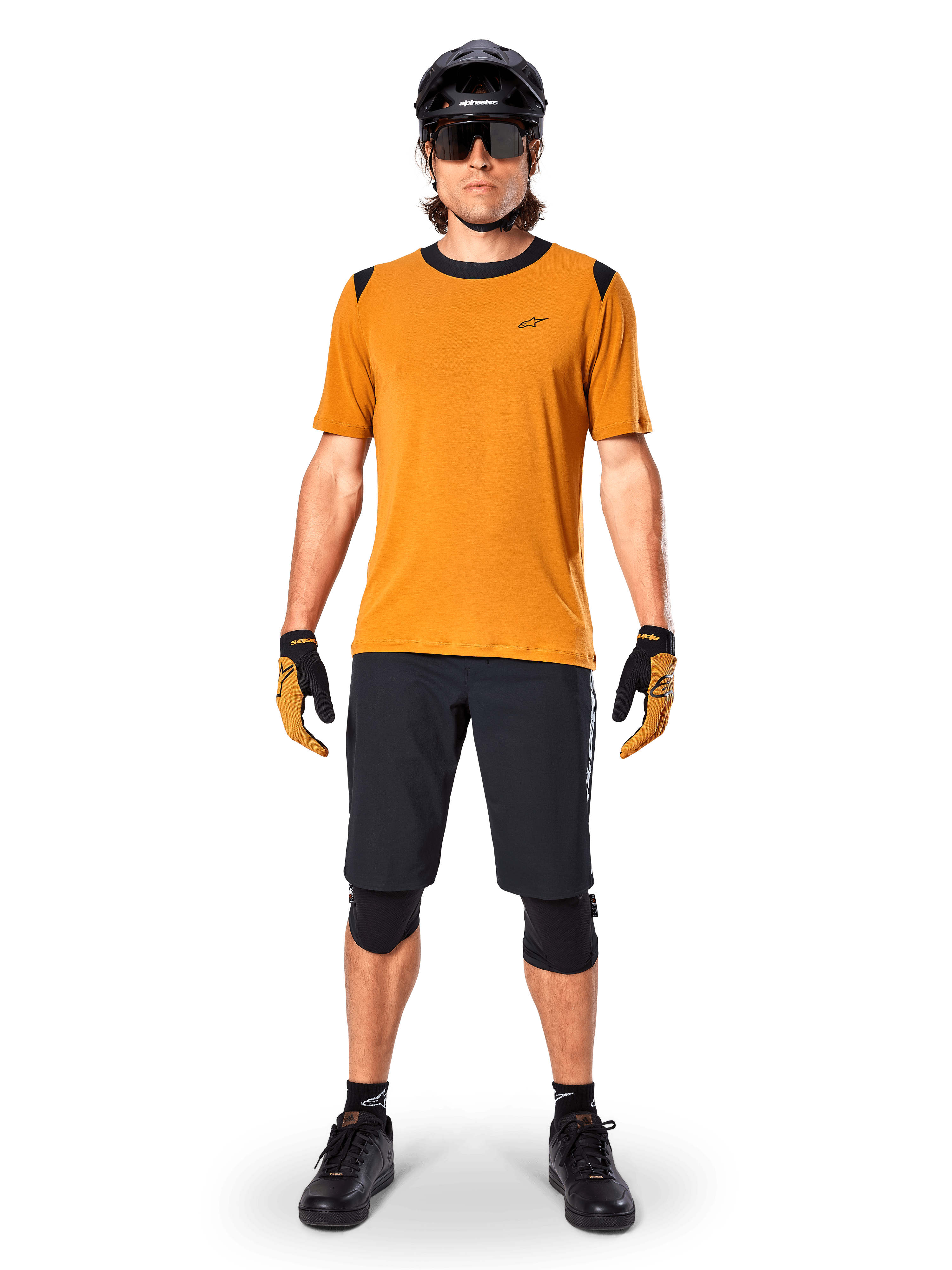 Alpinestars A-Dura Dri Wool Short Sleeve Jersey in Dark Gold, maglia da mountain bike a maniche corte, tessuto giallo senape con colletto e dettagli sulle spalle neri, indossata con pantaloncini neri e protezioni, abbigliamento tecnico da ciclismo per trail