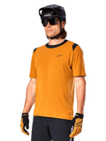 Alpinestars A-Dura Dri Wool Jersey - Short Sleeve, maglia da ciclismo MTB, oro scuro con dettagli neri, maglia tecnica a maniche corte in misto lana con inserti neri sulle spalle, indossata con casco da mountain bike nero e guanti coordinati