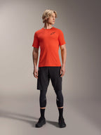 Maglia Alpinestars A-Aria Astar a maniche corte, Spicy Orange, indossata da un modello con pantaloncini neri da mountain bike e ginocchiere, abbigliamento tecnico da ciclismo leggero e traspirante per MTB