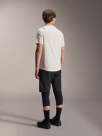 Alpinestars A-Aria Astar Jersey, maglia MTB a maniche corte, ecru, vista posteriore che mostra la vestibilità performante e la coda più lunga, abbinata a pantaloncini da mountain bike neri, protezioni per le ginocchia e scarpe da riding nere per sessioni trail off-road