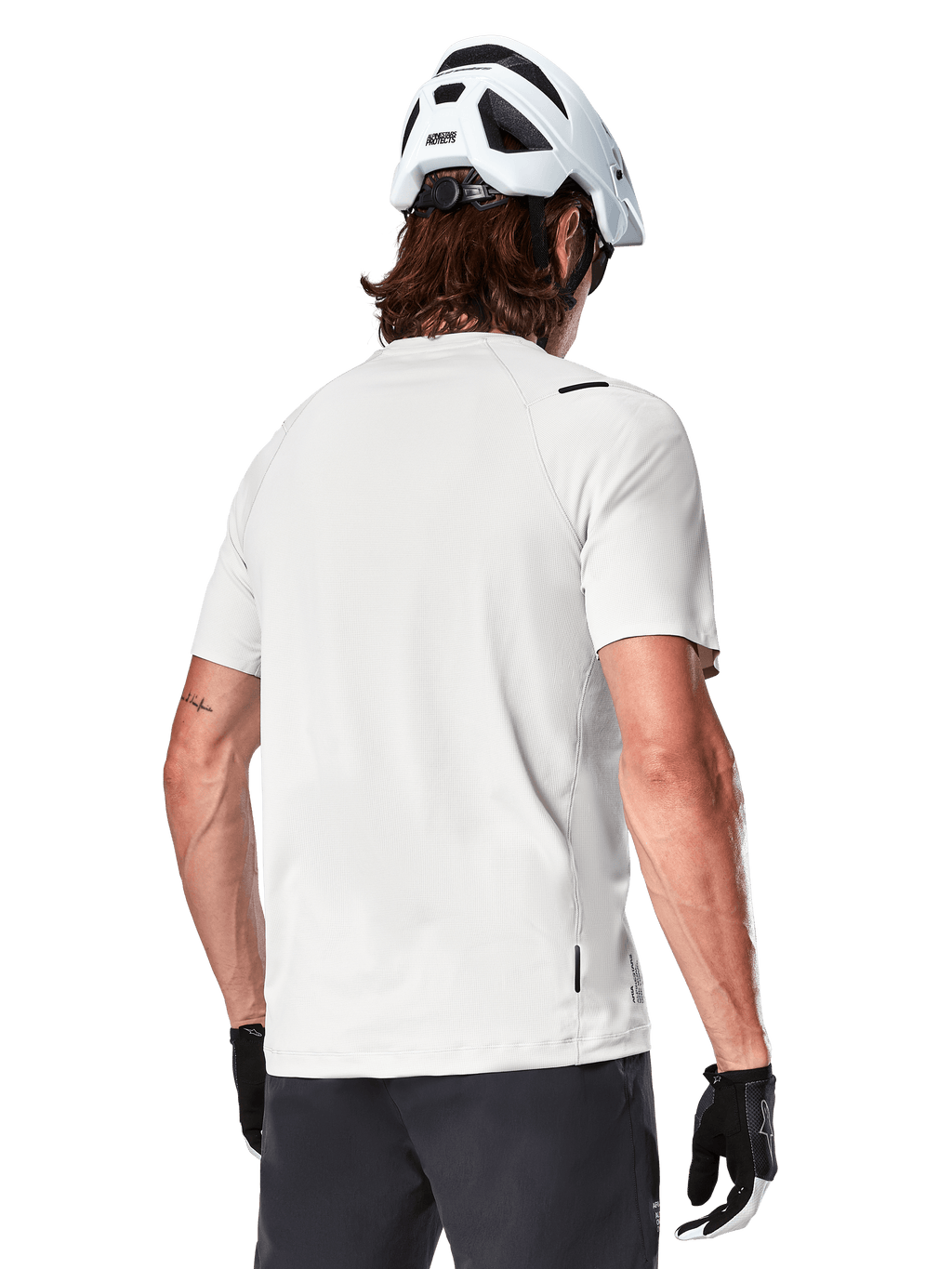 Alpinestars A-Aria Astar Jersey, maniche corte, White Dove, vista posteriore di maglia da mountain bike leggera e traspirante, indossata con casco bianco e guanti da ciclismo neri, con parte posteriore allungata per una maggiore copertura
