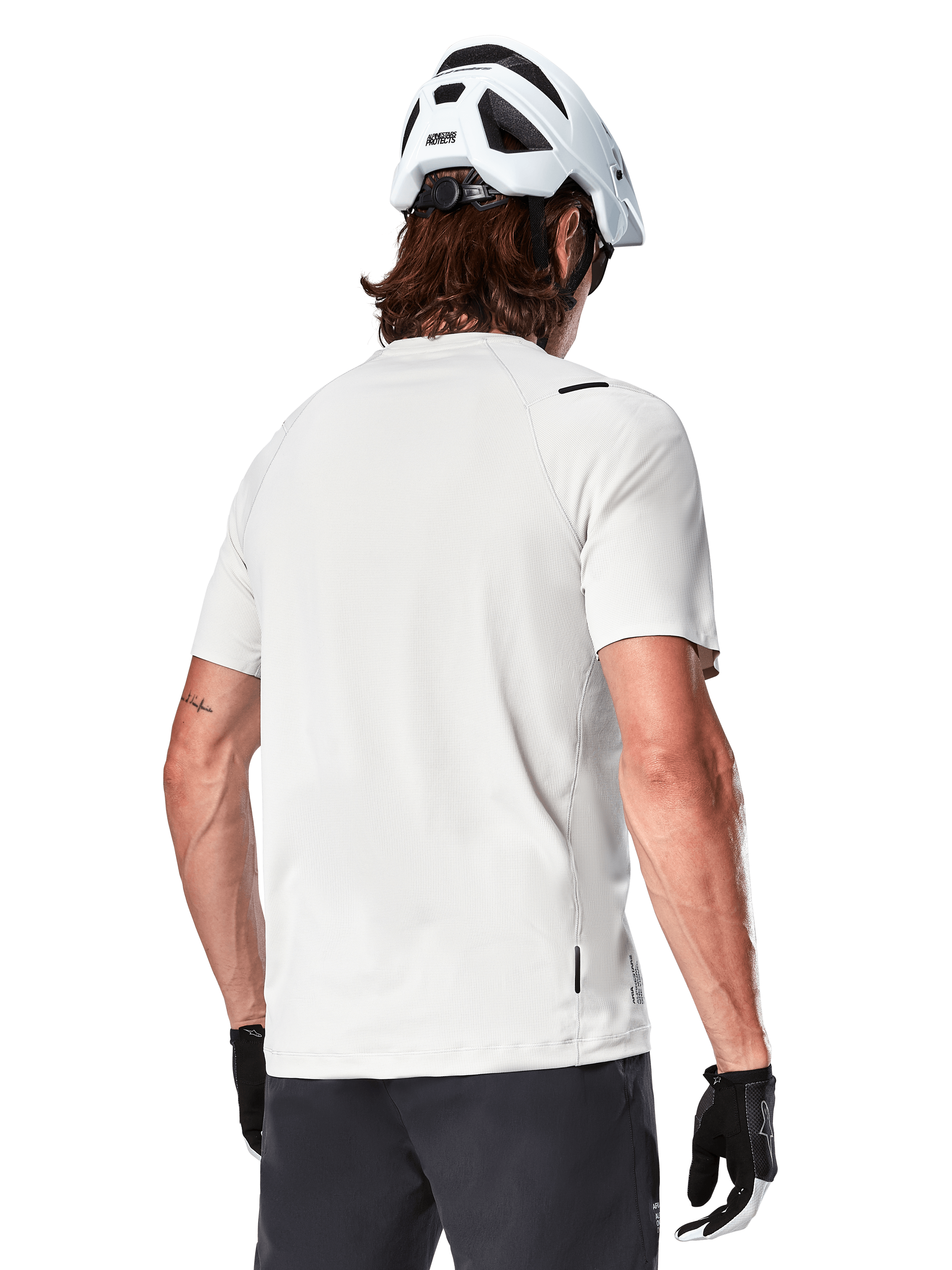 Alpinestars A-Aria Astar Jersey, maniche corte, White Dove, vista posteriore di maglia da mountain bike leggera e traspirante, indossata con casco bianco e guanti da ciclismo neri, con parte posteriore allungata per una maggiore copertura