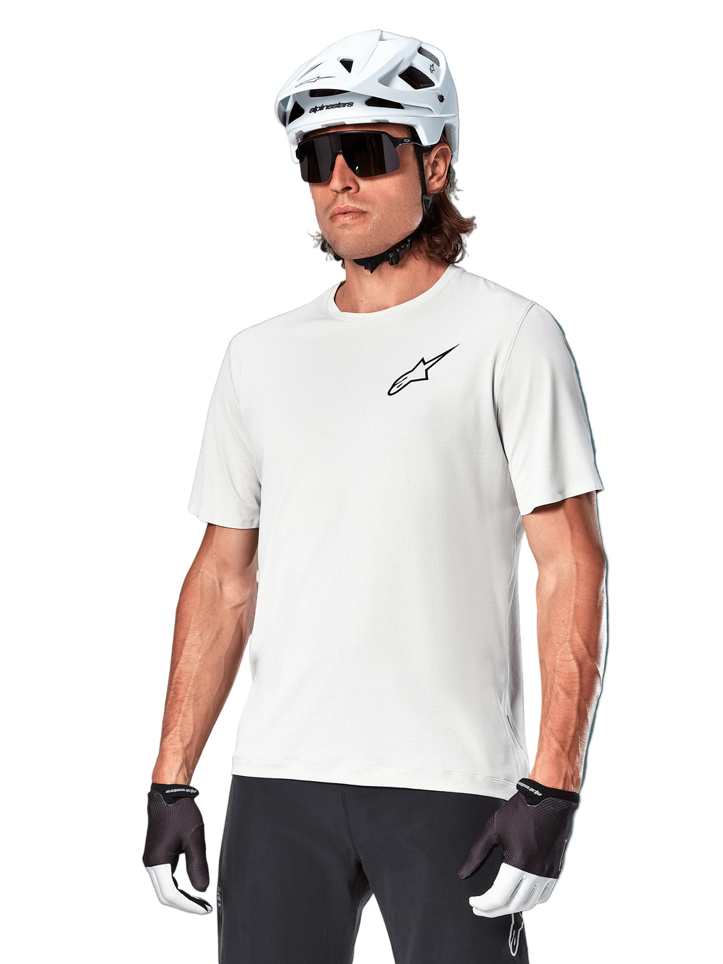 Alpinestars Maglia A-Aria Astar a maniche corte, White Dove, indossata da un ciclista con casco bianco e occhiali da sole scuri, con un piccolo logo a stella nero sul petto, abbigliamento performante traspirante per mountain bike