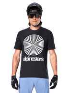 Alpinestars Maglia A-Dura Oscar, maglia MTB a maniche corte, nero, con una grande grafica a spirale vintage Oscar bianca sul petto, indossata con casco da ciclismo nero, occhiali da sole, guanti neri e pantaloncini azzurri, abbigliamento da ciclismo off-road d'ispirazione heritage