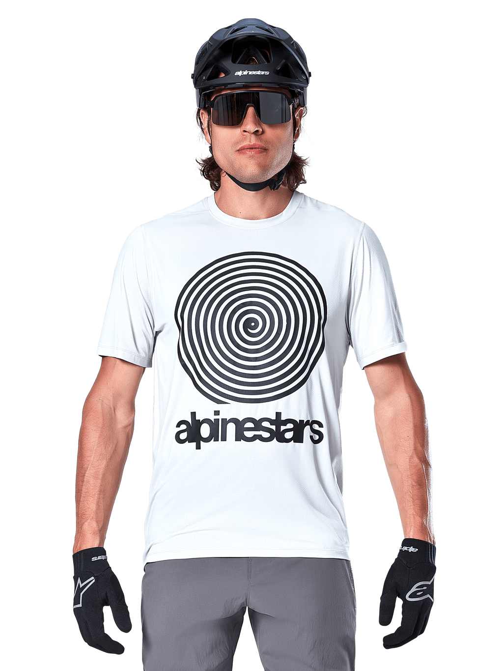 Maglia a maniche corte Alpinestars A-Dura Oscar, colore White Dove, con grande grafica vintage a spirale Oscar nera e scritta alpinestars sul petto, indossata da un modello con casco da MTB nero, occhiali da sole e guanti neri, stile cycling heritage.