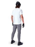 Maglia a maniche corte Alpinestars A-Dura Oscar in White Dove, vista posteriore indossata da un rider con pantaloni da ciclismo grigi, casco nero e guanti, abbigliamento tecnico da mountain bike per trail riding fuoristrada
