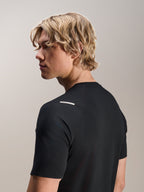 Uomo che indossa la maglia Alpinestars A-Aria Switch, a maniche corte, nero, vista laterale e posteriore che mostra la vestibilità performante e il dettaglio della spalla, abbigliamento da ciclismo MTB leggero e traspirante