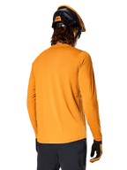 Maglia a maniche lunghe Alpinestars A-Dura Rocker, Dark Gold, vista posteriore del rider con casco da MTB nero e arancione, pantaloni scuri e guanti coordinati, abbigliamento da mountain bike casual ad alte prestazioni