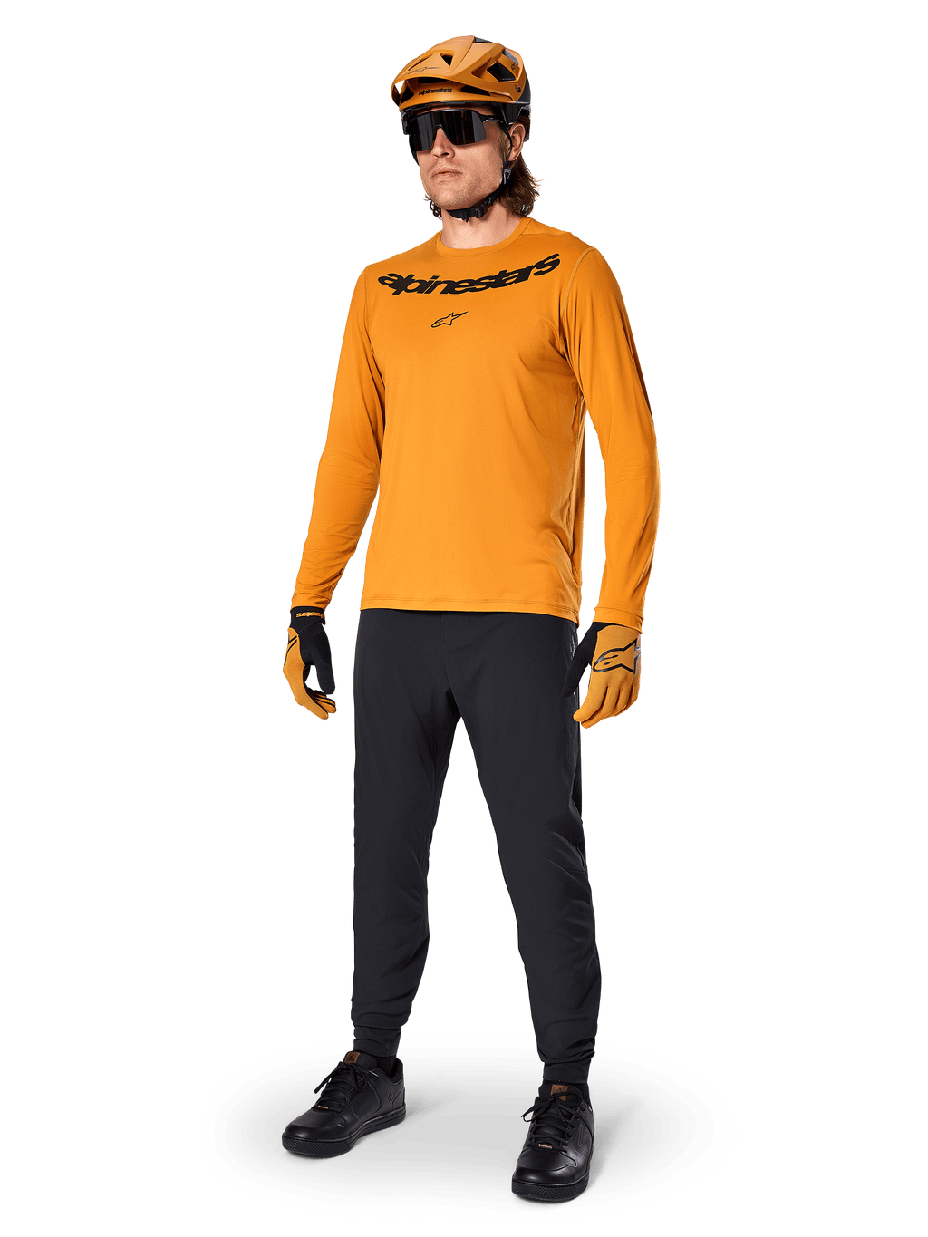 Alpinestars Maglia A-Dura Rocker Long Sleeve, maglia da ciclismo oro scuro, indossata con casco MTB coordinato e pantaloni neri, con logo nero sul petto, abbigliamento tecnico per mountain bike fuoristrada