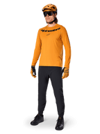Alpinestars Maglia A-Dura Rocker Long Sleeve, maglia da ciclismo oro scuro, indossata con casco MTB coordinato e pantaloni neri, con logo nero sul petto, abbigliamento tecnico per mountain bike fuoristrada