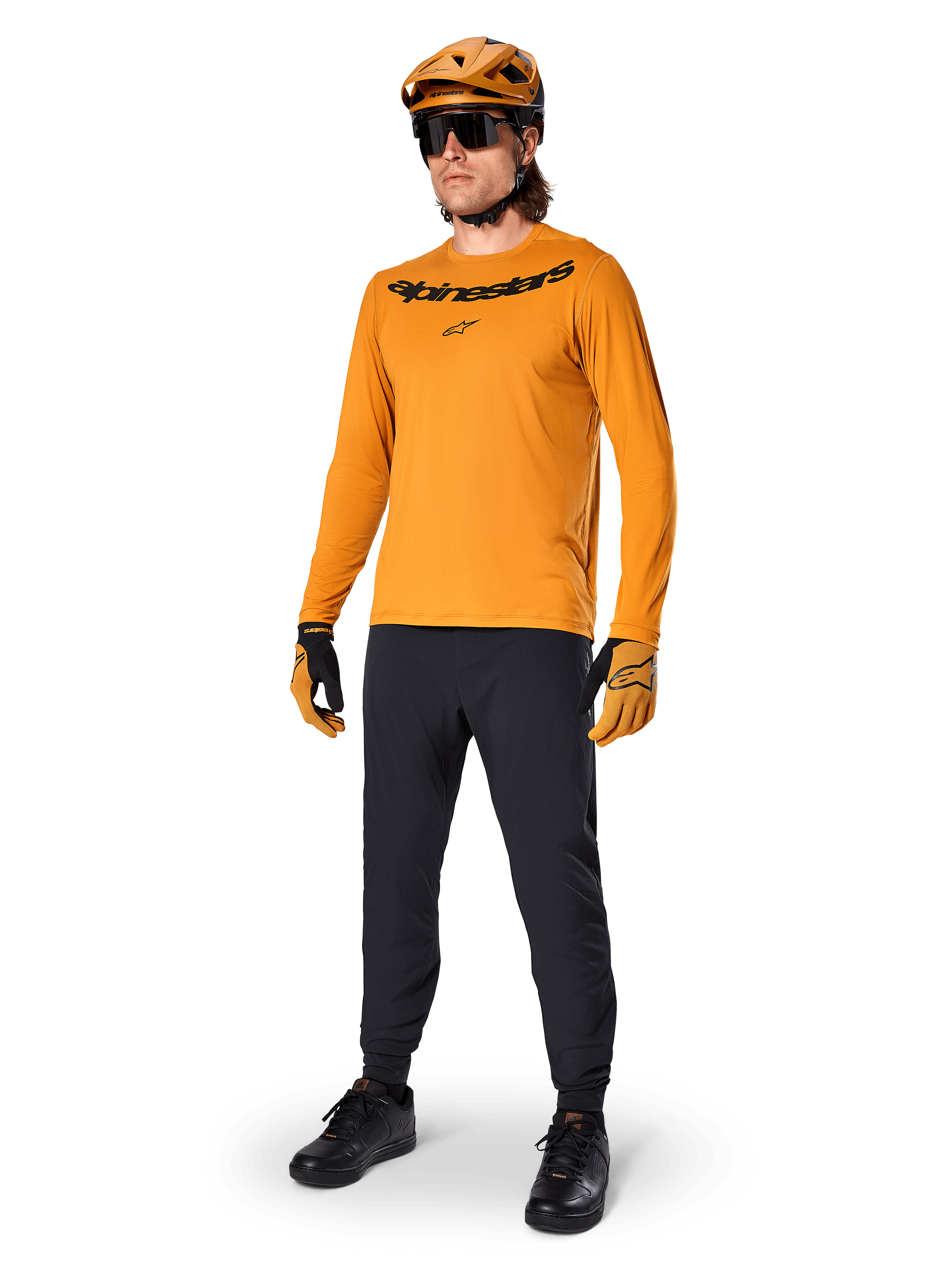 Alpinestars Maglia A-Dura Rocker Long Sleeve, maglia da ciclismo oro scuro, indossata con casco MTB coordinato e pantaloni neri, con logo nero sul petto, abbigliamento tecnico per mountain bike fuoristrada