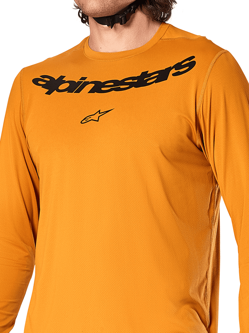 Alpinestars A-Dura Rocker Long Sleeve Jersey, oro scuro, vista ravvicinata del petto con scritta Alpinestars e logo a stella neri, tessuto jacquard testurizzato traspirante, abbigliamento tecnico da ciclismo MTB