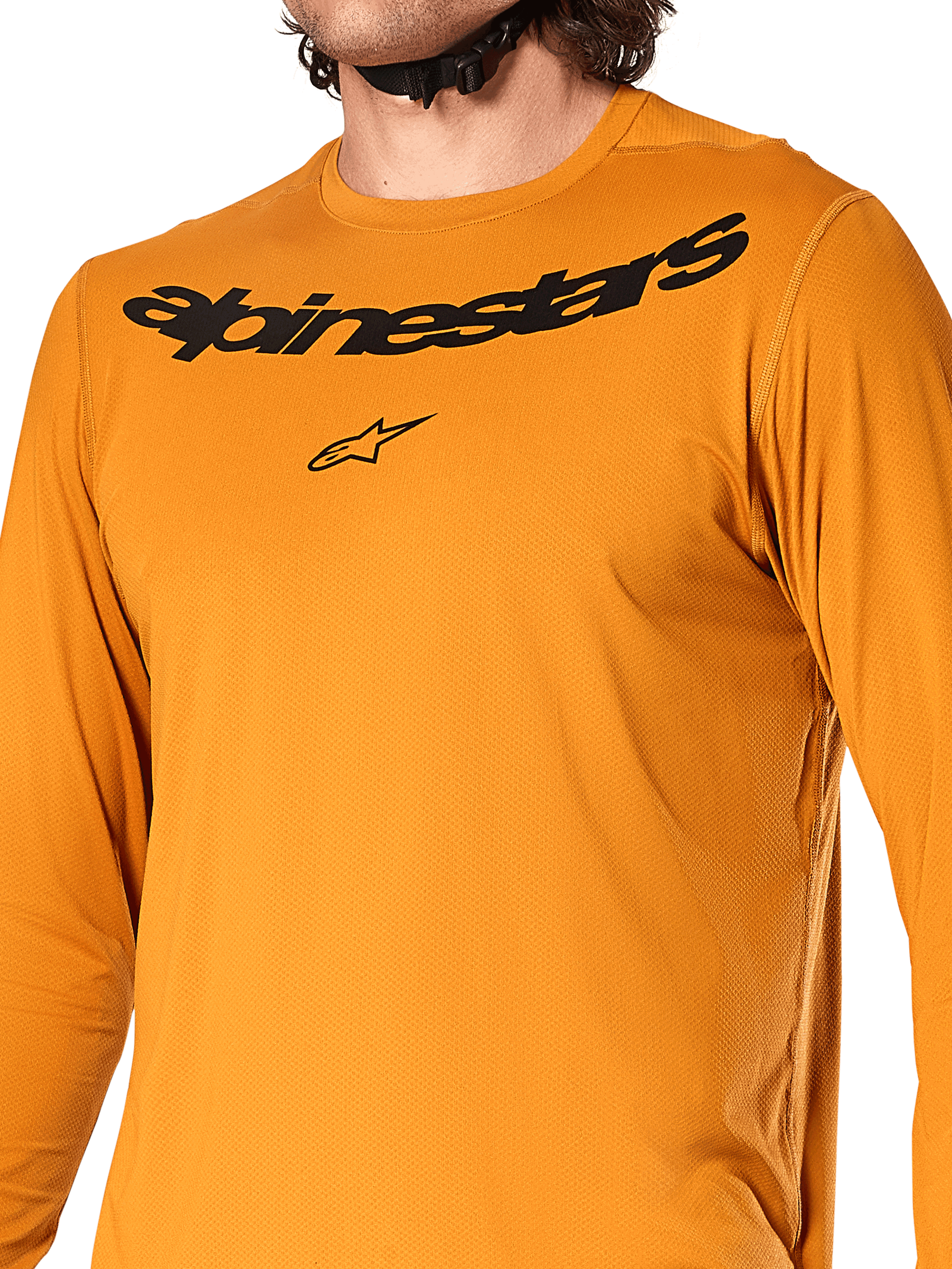 Alpinestars A-Dura Rocker Long Sleeve Jersey, oro scuro, vista ravvicinata del petto con scritta Alpinestars e logo a stella neri, tessuto jacquard testurizzato traspirante, abbigliamento tecnico da ciclismo MTB