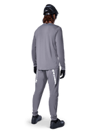 Maglia Alpinestars A-Dura Rocker a maniche lunghe, grigio scuro, vista posteriore del modello con pantaloni da MTB grigi coordinati, casco nero e guanti neri, design professionale per mountain bike