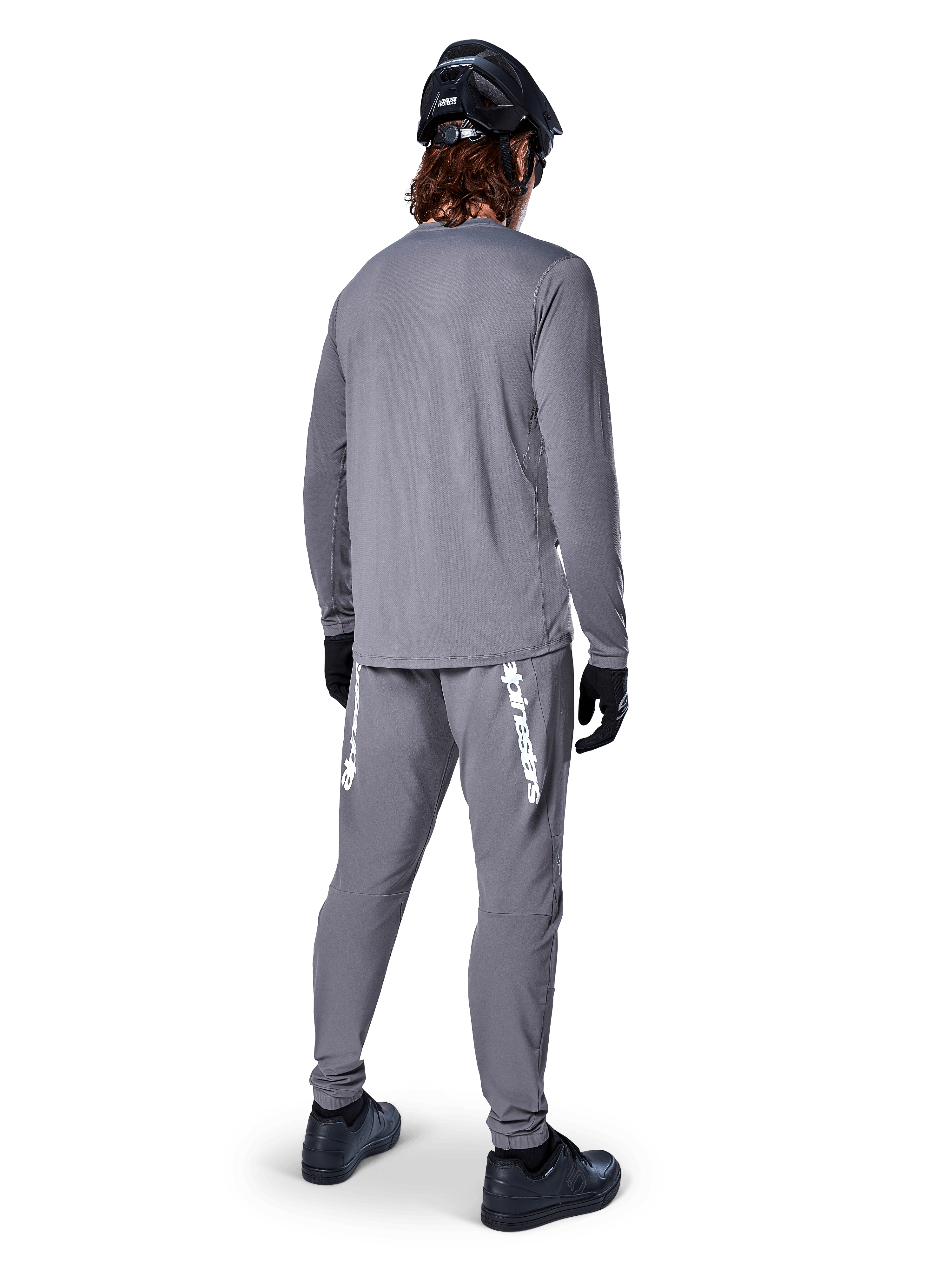 Maglia Alpinestars A-Dura Rocker a maniche lunghe, grigio scuro, vista posteriore del modello con pantaloni da MTB grigi coordinati, casco nero e guanti neri, design professionale per mountain bike