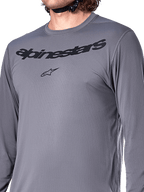 Alpinestars A-Dura Rocker Long Sleeve Jersey, grigio scuro, primo piano del petto con scritta Alpinestars e logo a stella neri, materiale jacquard poliestere-spandex, abbigliamento tecnico da mountain bike