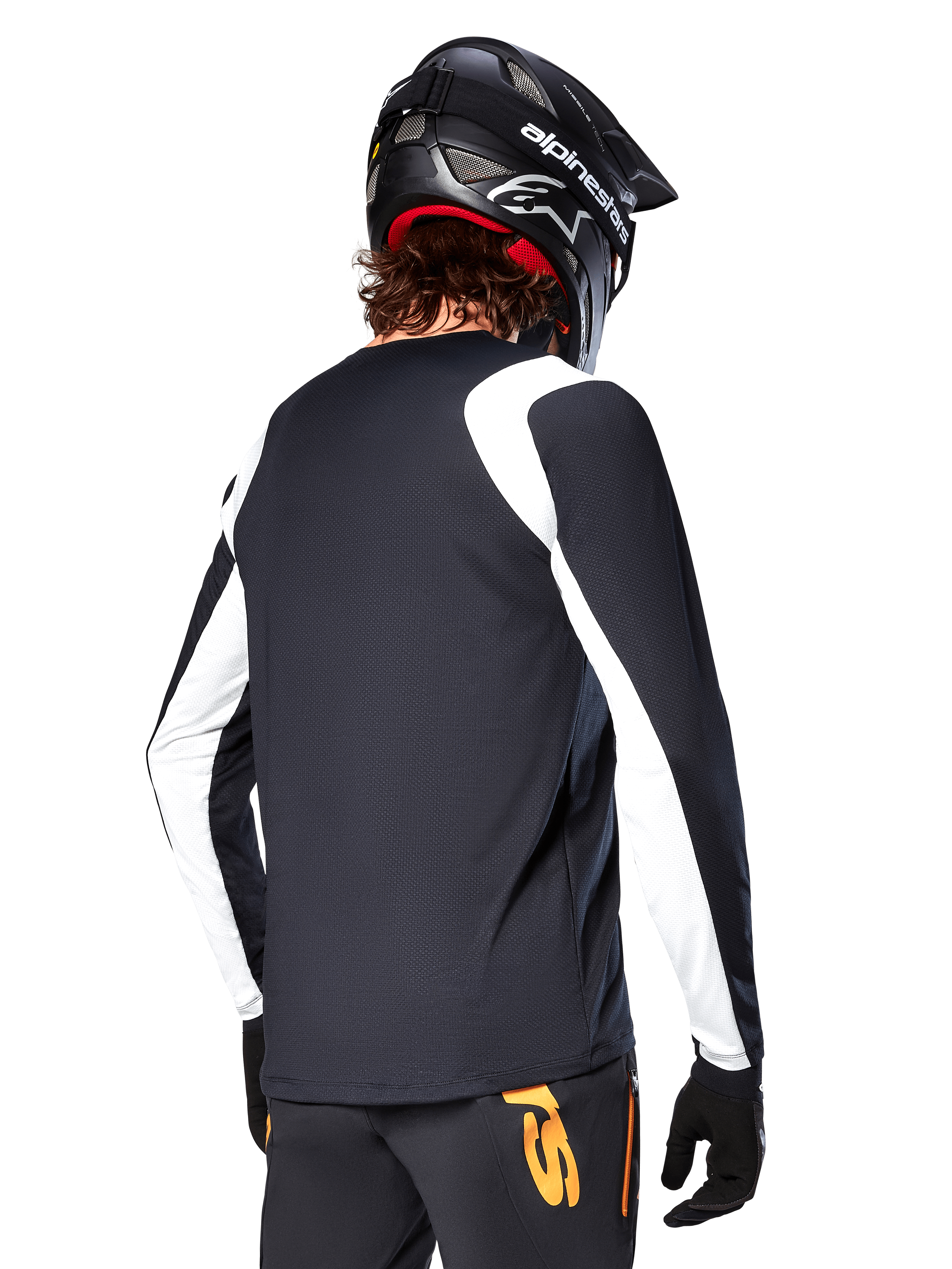 Ciclista MTB con maglia a maniche lunghe Alpinestars A-Supra Oscar, nero con pannelli bianchi sulle spalle e sulle maniche, vista posteriore, casco e guanti neri, pantaloni con accenti arancioni, abbigliamento da ciclismo fuoristrada resistente