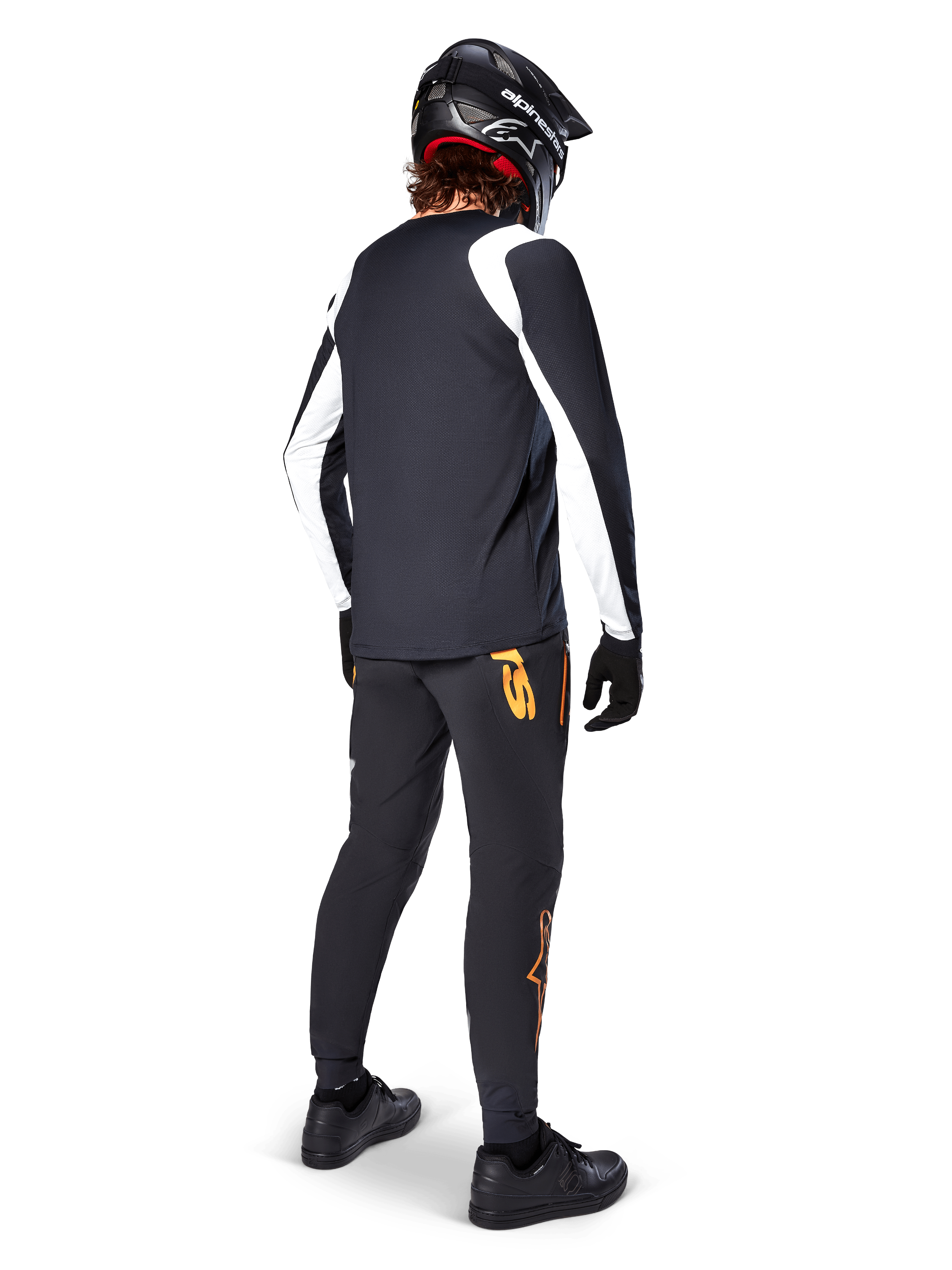 Maglia a maniche lunghe Alpinestars A-Supra Oscar, nera con pannelli bianchi sulle maniche, indossata da un rider MTB vista dal retro con casco integrale nero e pantaloni neri con loghi arancioni, abbigliamento da ciclismo per gravity off-road