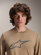 Maglia a maniche lunghe Alpinestars A-Dura Astar, marrone chiaro, indossata da un modello, con grande logo Astars sul petto, trama in tessuto jacquard, abbigliamento casual da mountain bike