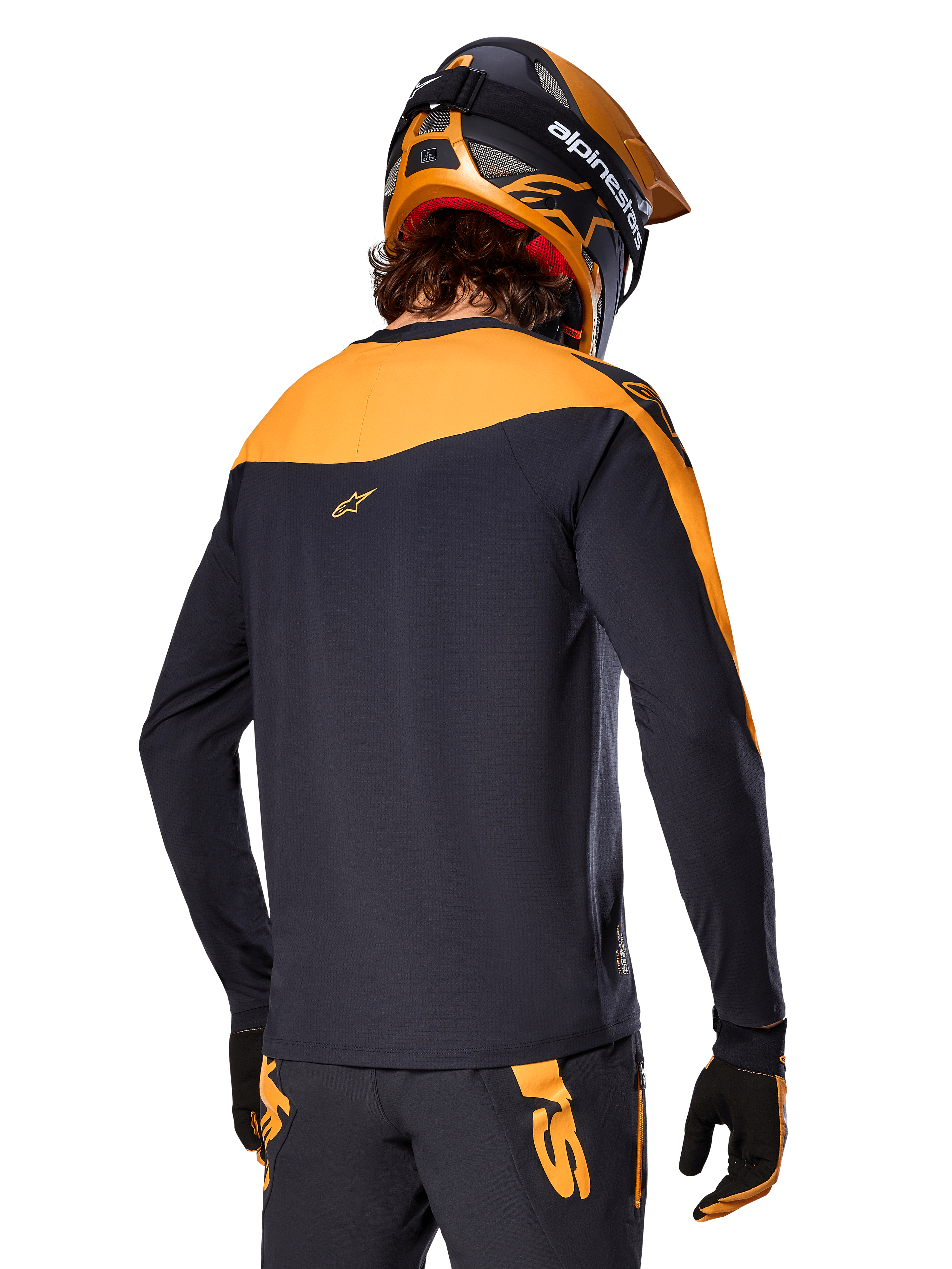Alpinestars Maglia A-Supra Race - Maniche lunghe, nero e arancione, vista posteriore del pilota con casco e pantaloni da mountain bike coordinati, vestibilità performance con texture microperforata, abbigliamento professionale da gara MTB