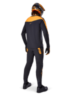 Alpinestars A-Supra Race Jersey - Maniche Lunghe, nero e arancione, vista posteriore di un rider che indossa pantaloni MTB coordinati, casco e guanti arancione e nero, abbigliamento tecnico per gare di mountain bike