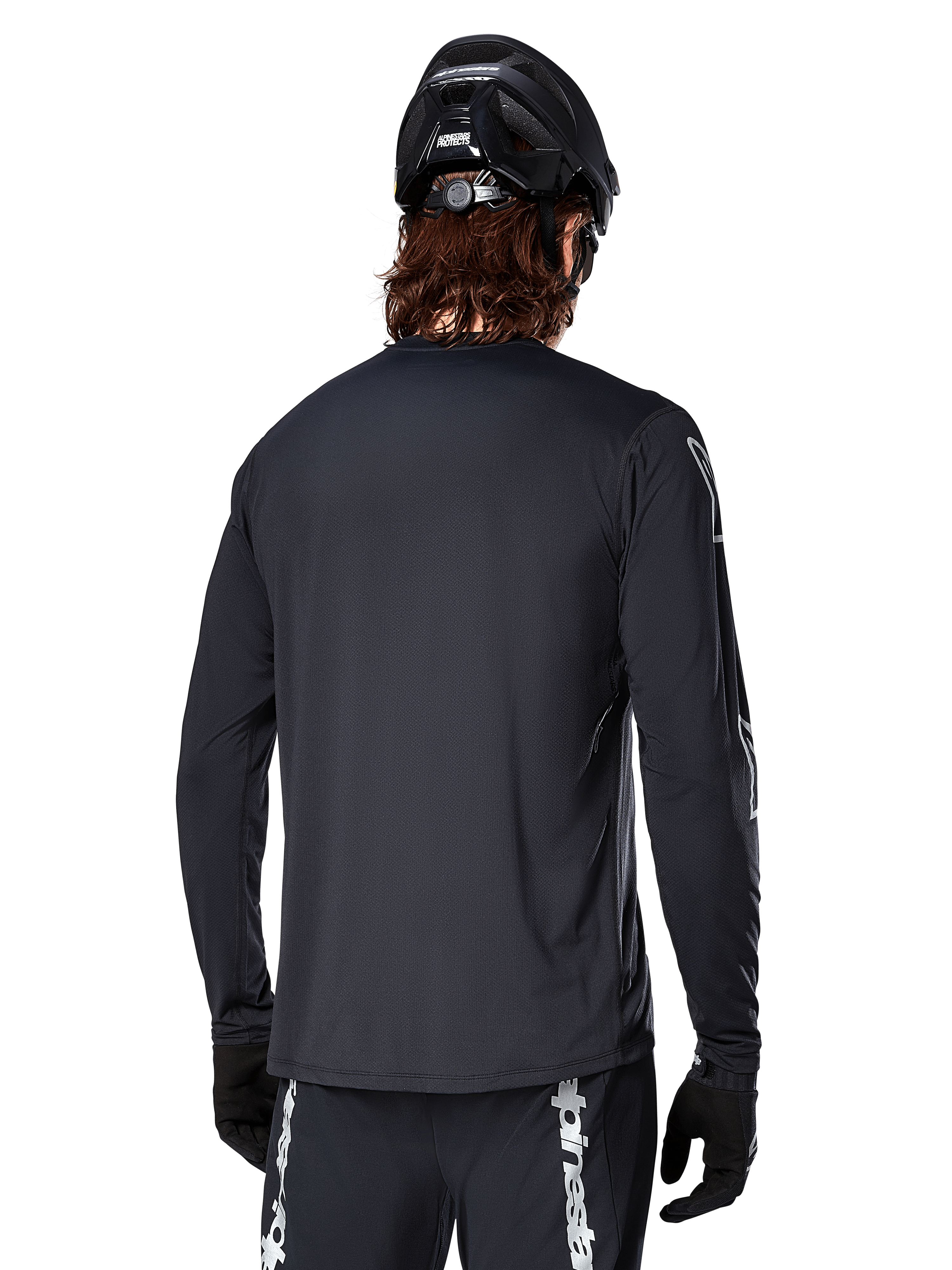 Maglia a maniche lunghe Alpinestars A-Dura Switch, nera, vista posteriore su un ciclista con casco MTB nero e guanti, in tessuto tecnico jacquard e con coda allungata per il fuoristrada