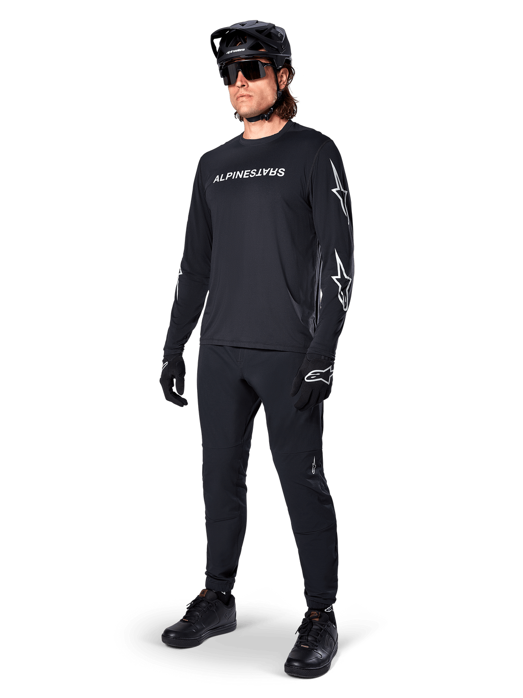 Maglia a maniche lunghe Alpinestars A-Dura Switch, nero, maglia da mountain bike indossata con pantaloni neri, casco e guanti, con logo wordmark bianco sul petto e loghi a stella sulle maniche, equipaggiamento MTB coordinato per la guida fuoristrada