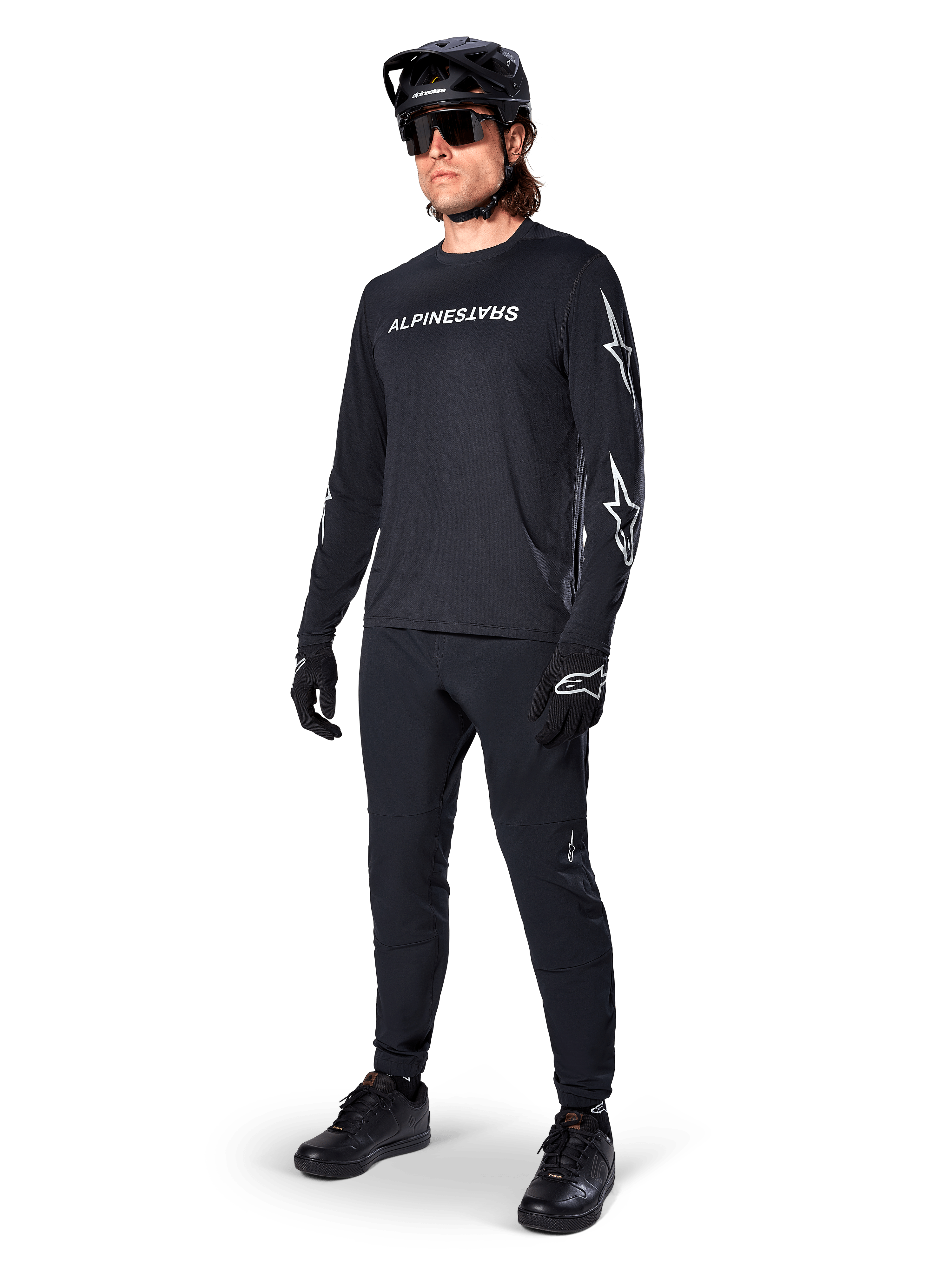 Maglia a maniche lunghe Alpinestars A-Dura Switch, nero, maglia da mountain bike indossata con pantaloni neri, casco e guanti, con logo wordmark bianco sul petto e loghi a stella sulle maniche, equipaggiamento MTB coordinato per la guida fuoristrada