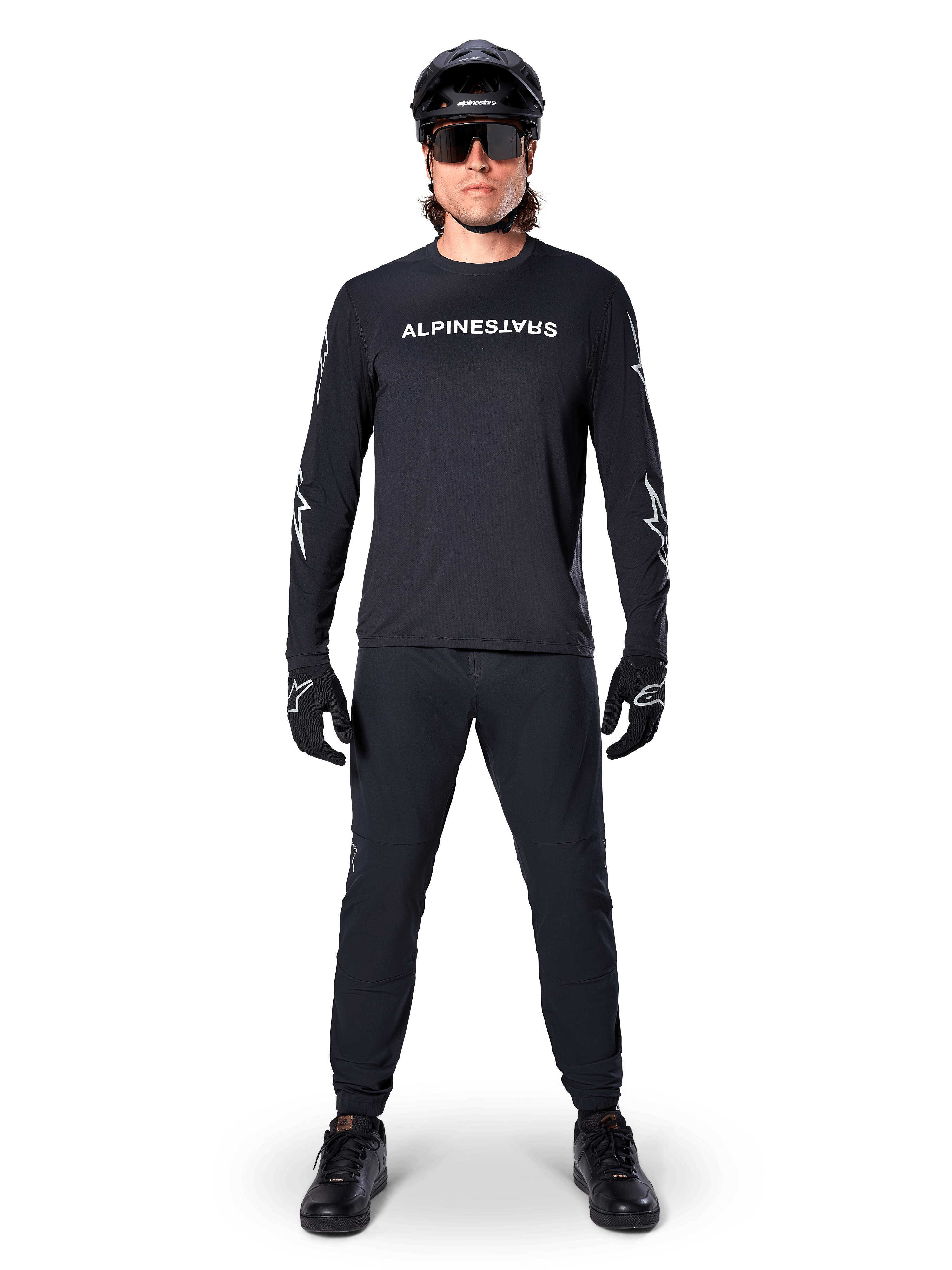 Maglia Alpinestars A-Dura Switch a maniche lunghe, nero, indossata da un ciclista di mountain bike con pantaloni e casco neri coordinati, con logo wordmark bianco sul petto, abbigliamento tecnico per ciclismo fuoristrada