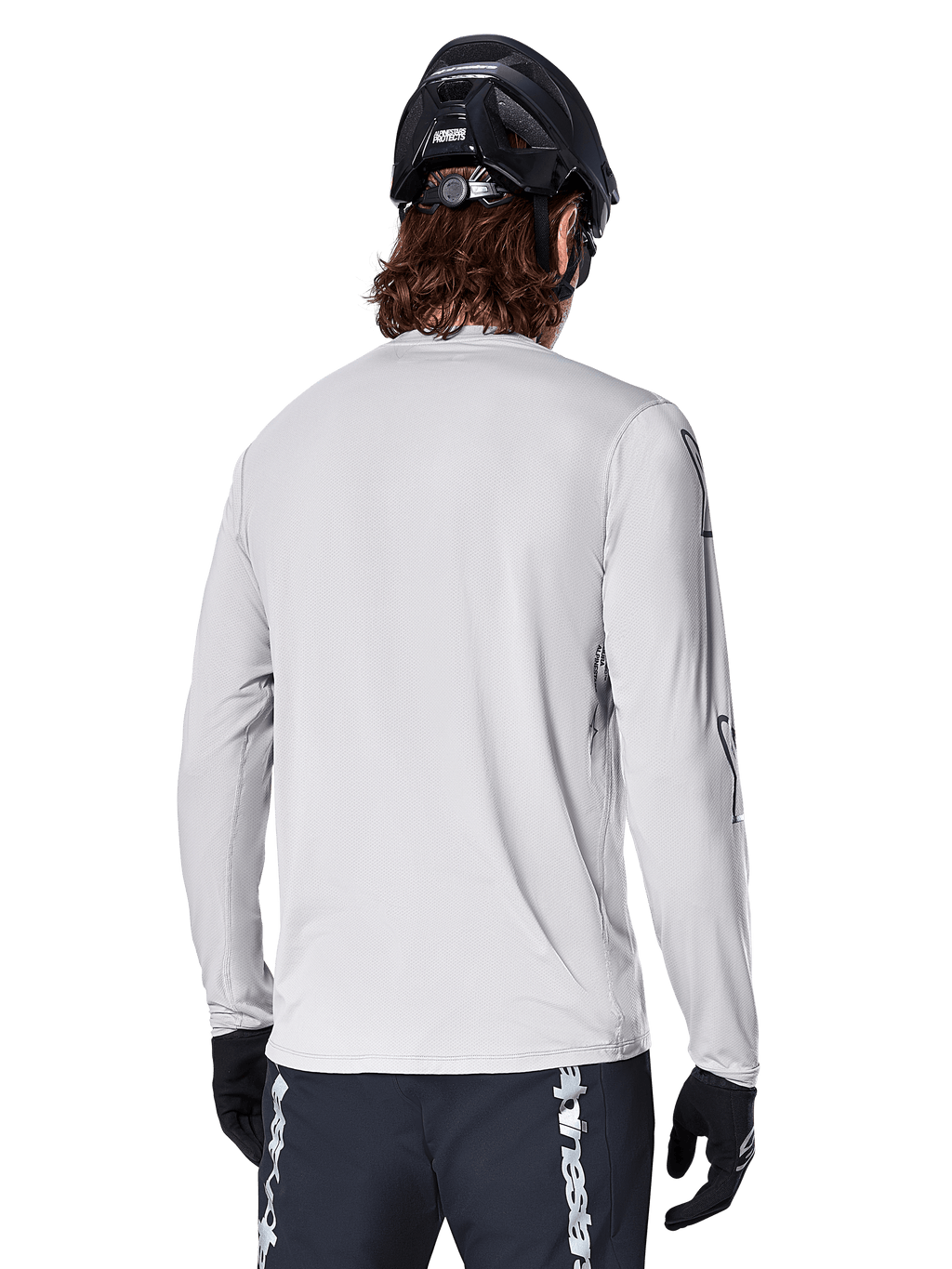 Alpinestars Maglia A-Dura Switch Long Sleeve, Grigio Chiaro, vista posteriore di un mountain biker con casco da MTB nero e guanti, con coda posteriore allungata e tessuto jacquard, abbigliamento tecnico da ciclismo