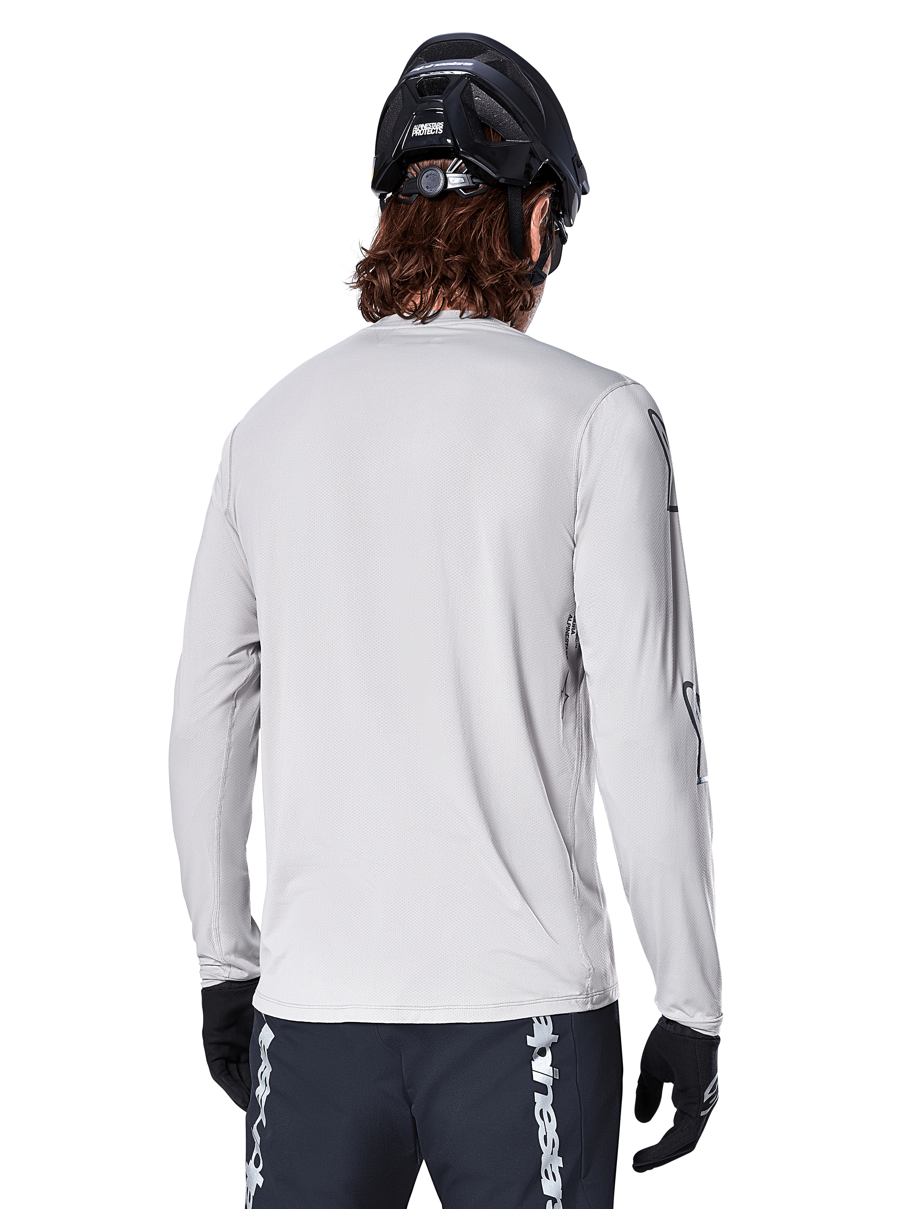 Alpinestars Maglia A-Dura Switch Long Sleeve, Grigio Chiaro, vista posteriore di un mountain biker con casco da MTB nero e guanti, con coda posteriore allungata e tessuto jacquard, abbigliamento tecnico da ciclismo