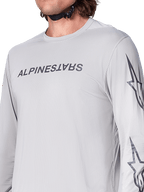 Alpinestars A-Dura Switch Jersey - Long Sleeve, maglia da mountain bike grigio chiaro con marchio a scritte grigio scuro sul petto e logo a stella sulla manica, texture jacquard traspirante, abbigliamento tecnico per trail riding