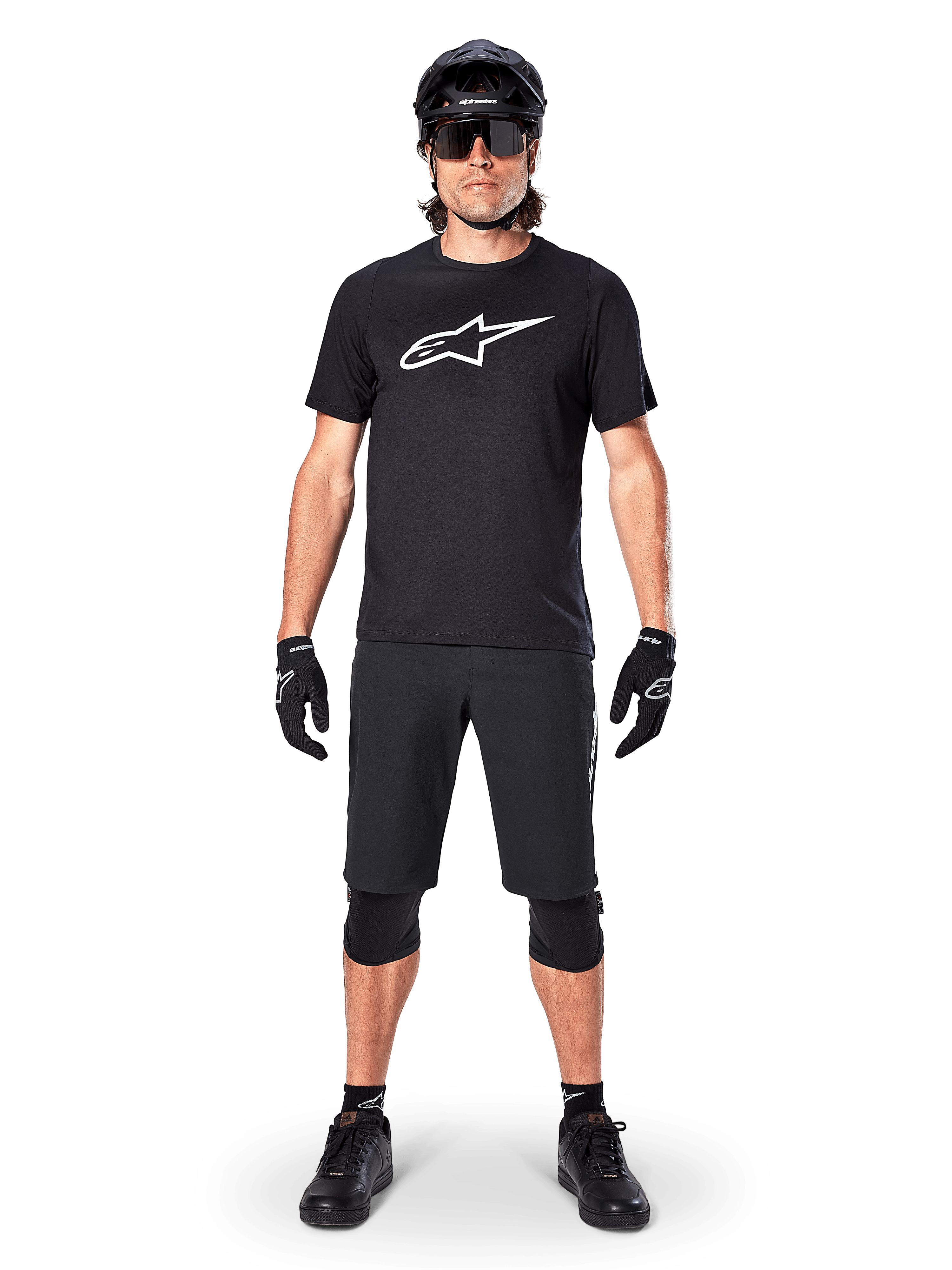 Alpinestars A-Dura Dri Oscar Short Sleeve Jersey, nero riflettente, indossata con pantaloncini da MTB neri coordinati, guanti, ginocchiere e casco, con un grande logo Alpinestars bianco sul petto, abbigliamento completo da mountain bike