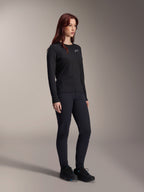 Donna che indossa la maglia Alpinestars Stella A-Dura Thermal Jersey, maglia MTB nera a maniche lunghe con logo bianco sul petto, abbinata a pantaloni neri coordinati e scarpe sportive, ritratto in studio per abbigliamento tecnico da ciclismo
