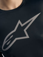 Dettaglio logo Alpinestars grigio su maglia Stella A-Dura Ride nera a maniche lunghe, tessuto jacquard MTB donna.