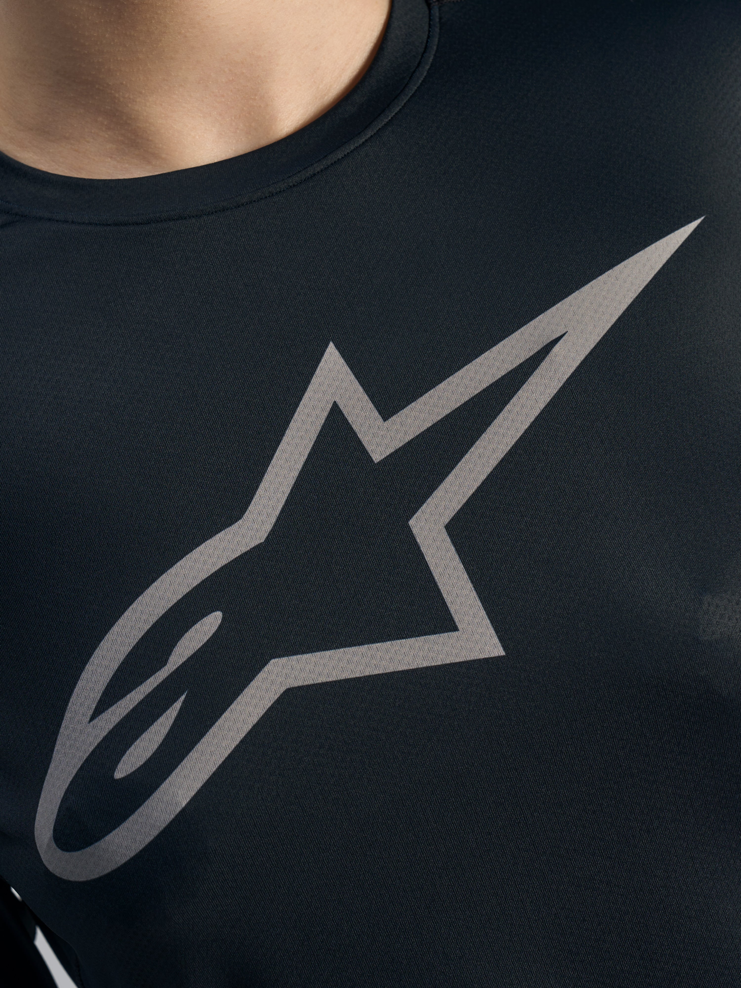 Dettaglio logo Alpinestars grigio su maglia Stella A-Dura Ride nera a maniche lunghe, tessuto jacquard MTB donna.