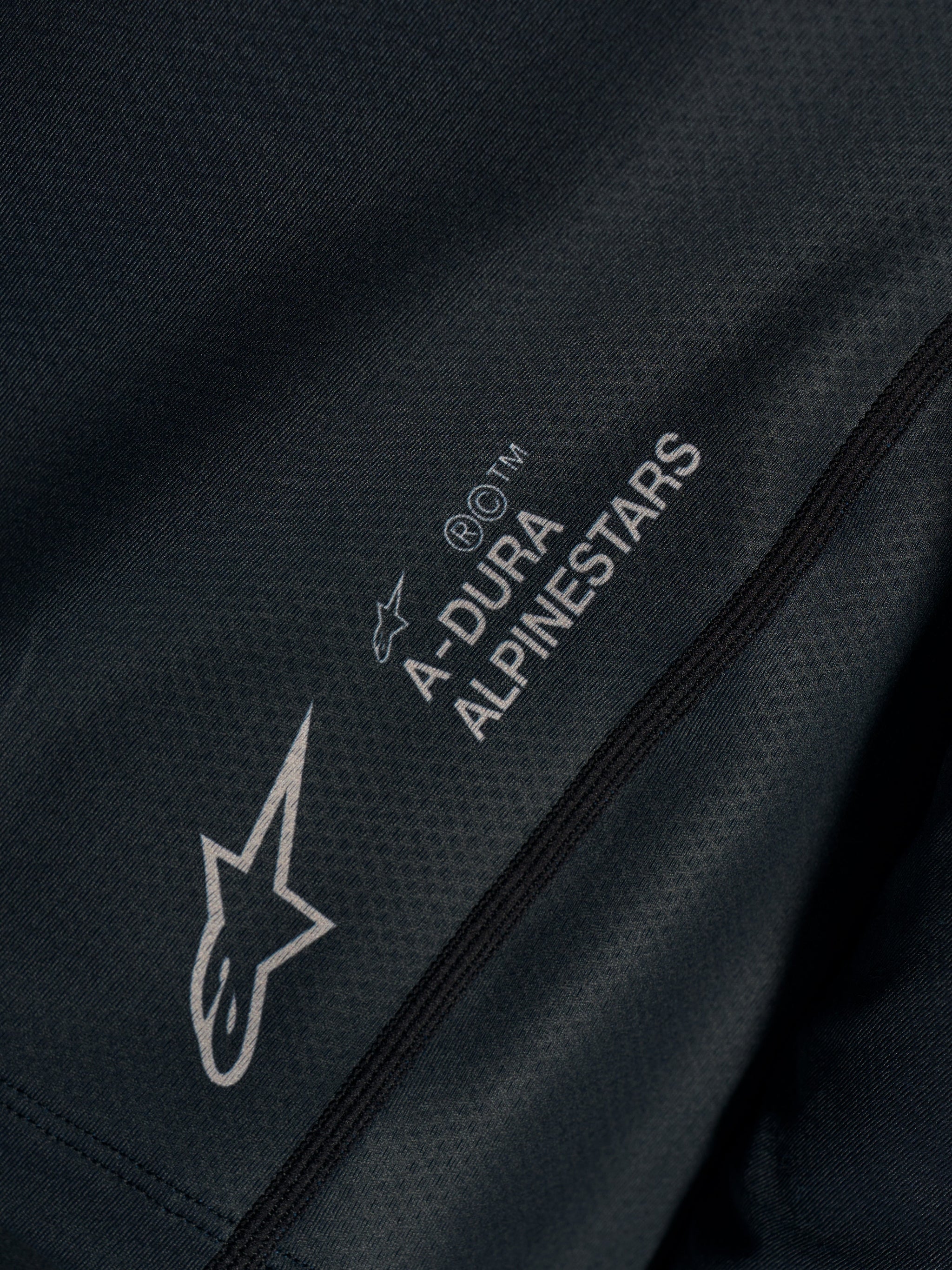 Dettaglio maglia Stella A-Dura Ride nera in tessuto tecnico jacquard con loghi A-DURA ALPINESTARS e Astars.