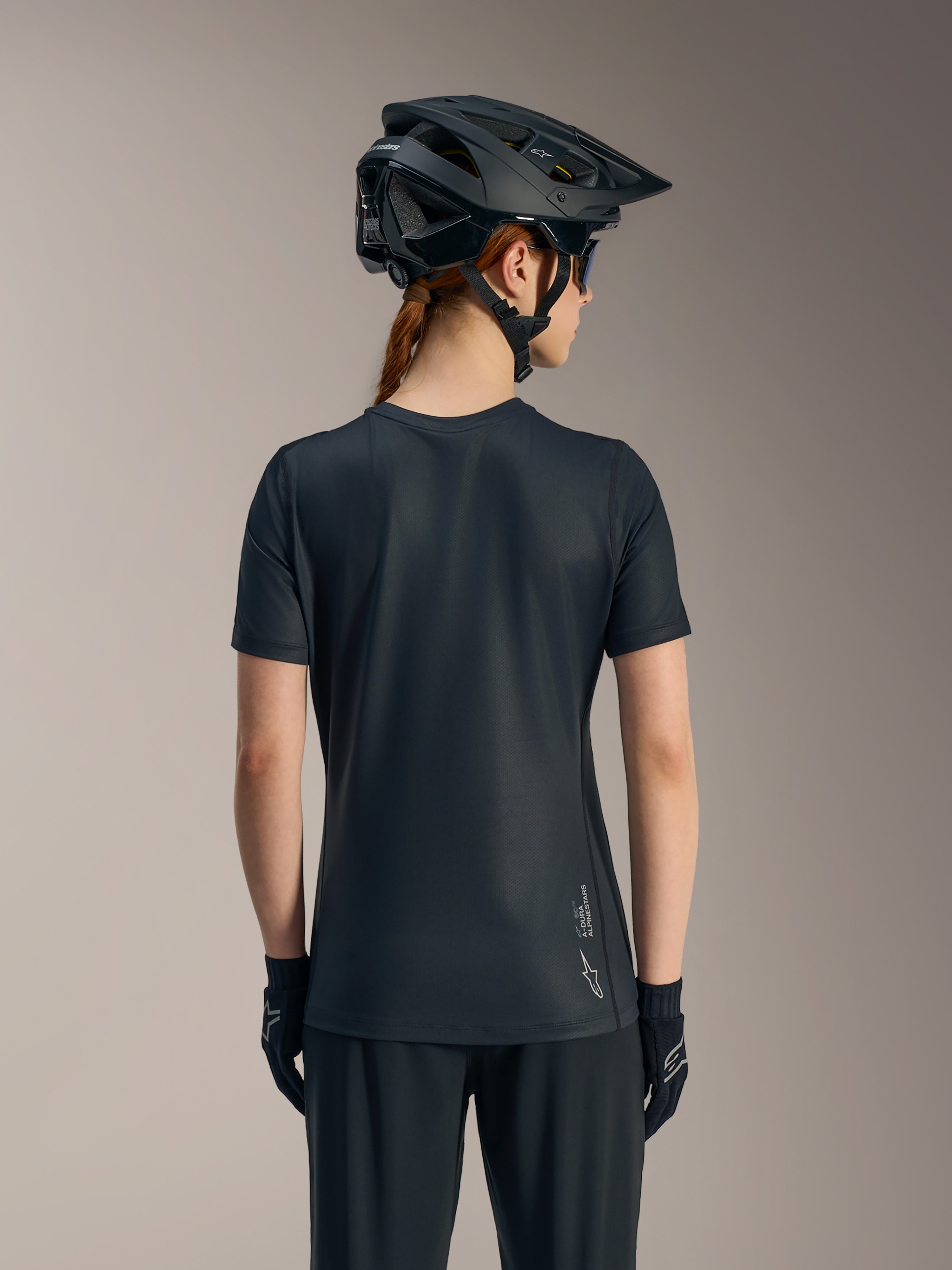 Maglia Stella A-Dura Ride nera a maniche corte da donna, vista posteriore con coda allungata e logo Alpinestars.