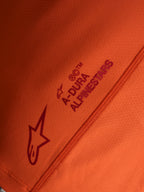 Maglia arancione Stella A-Dura Ride, dettaglio logo Alpinestars e scritta A-DURA su tessuto stretch tecnico.