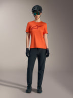 Maglia Alpinestars Stella A-Dura Ride arancione con logo bordeaux, abbinata a outfit MTB nero, casco e guanti.