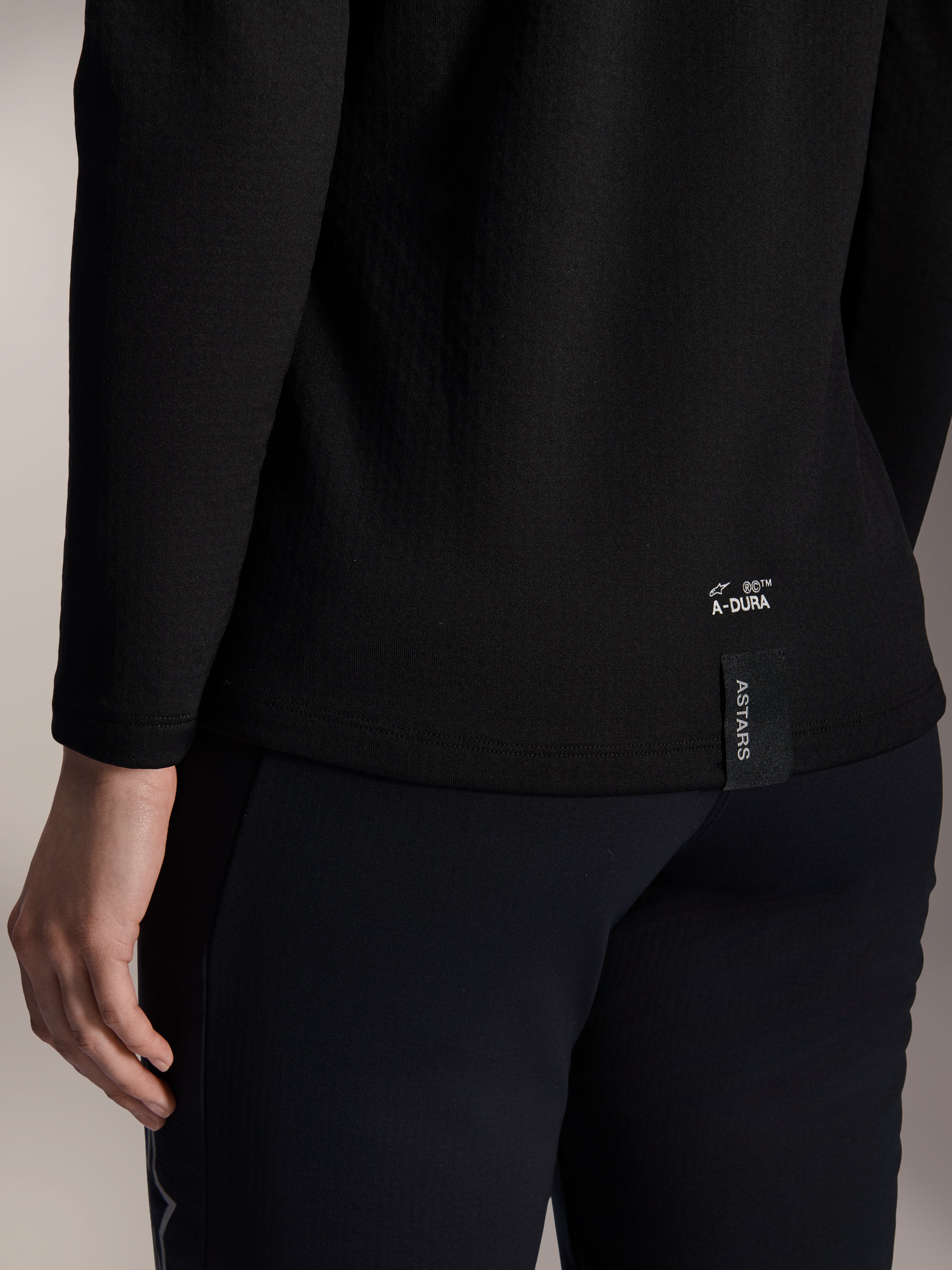 Alpinestars Stella A-Dura Thermal Jersey da donna, maglia termica da MTB nera, primo piano del bordo inferiore posteriore con branding A-DURA bianco ed etichetta logo ASTARS verticale, abbigliamento per mountain bike in climi freddi